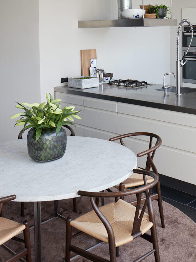 Modern kitchen with marble table and wooden chairs, needs organization