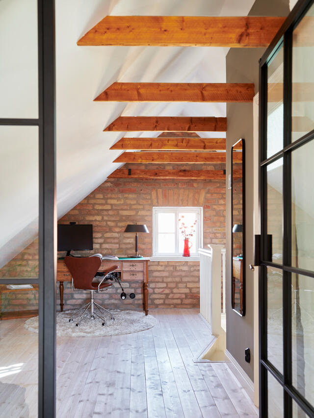 Oficina en casa en el ático con vigas de madera y soluciones Elfa