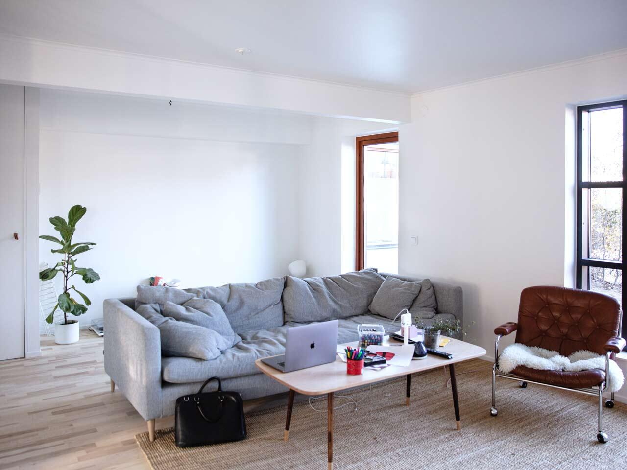 Minimalist living room with grey sofa and wooden table, before storage