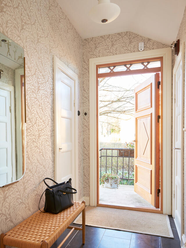Johanna Permsjö Entrada elegante con papel pintado estampado y banco de madera, necesita organización
