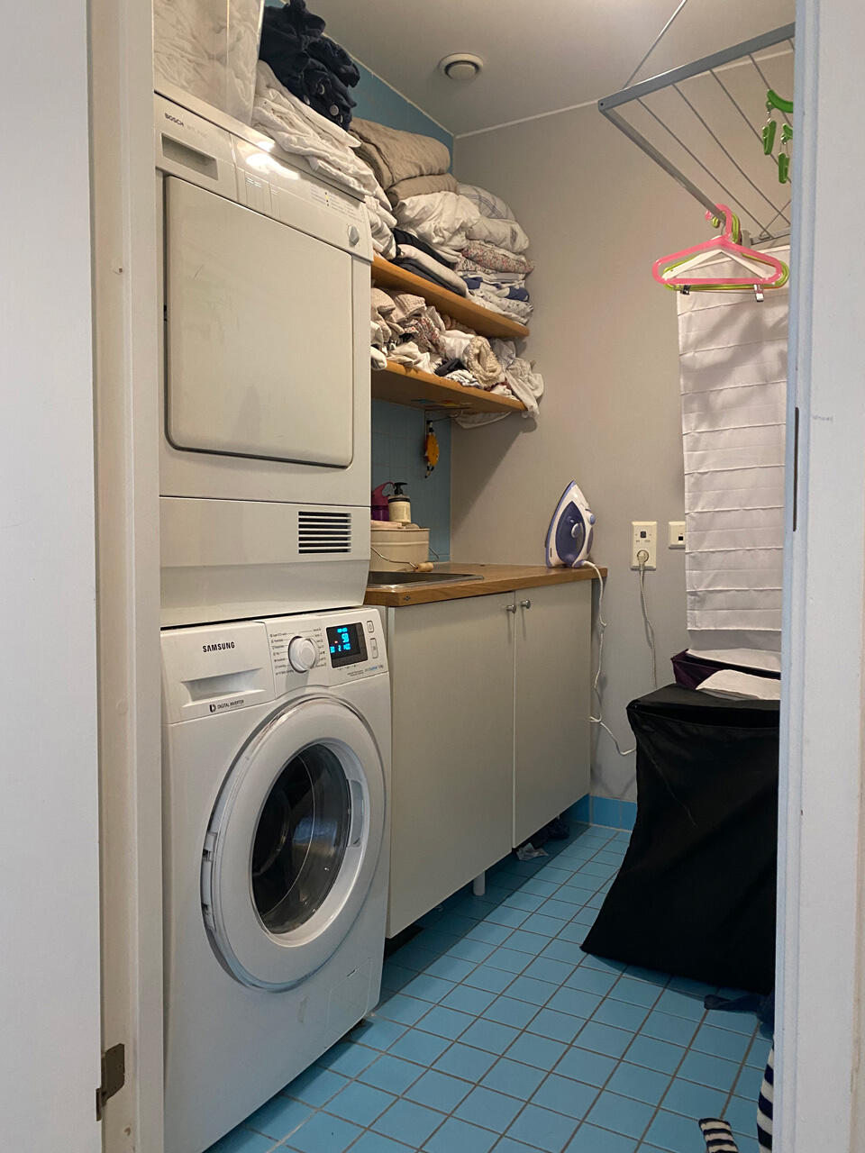 Niki Barntmark Lavadero desordenado con ropa de cama y electrodomésticos apilados, necesita organización