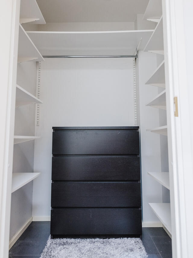 Natalie Armario blanco sencillo con cajonera negra y estantes minimalistas, a la espera de una solución de almacenamiento a medida