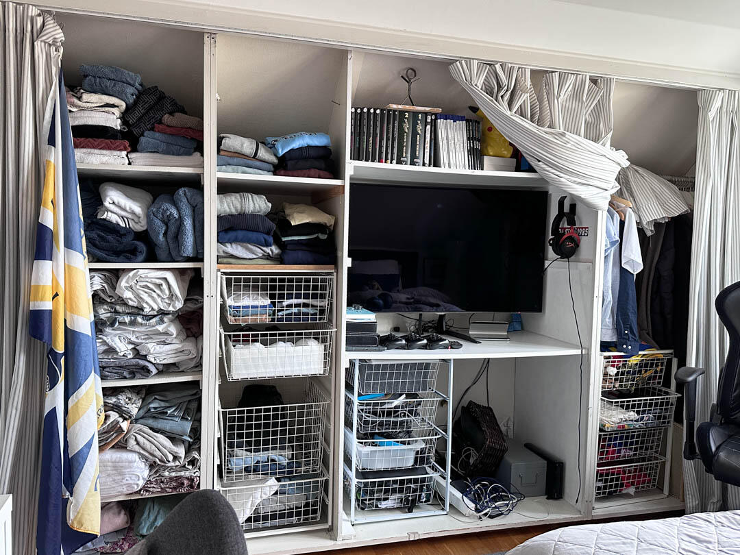 Prowizoryczna szafa z drucianymi koszami i centrum multimedialnym przed modernizacją