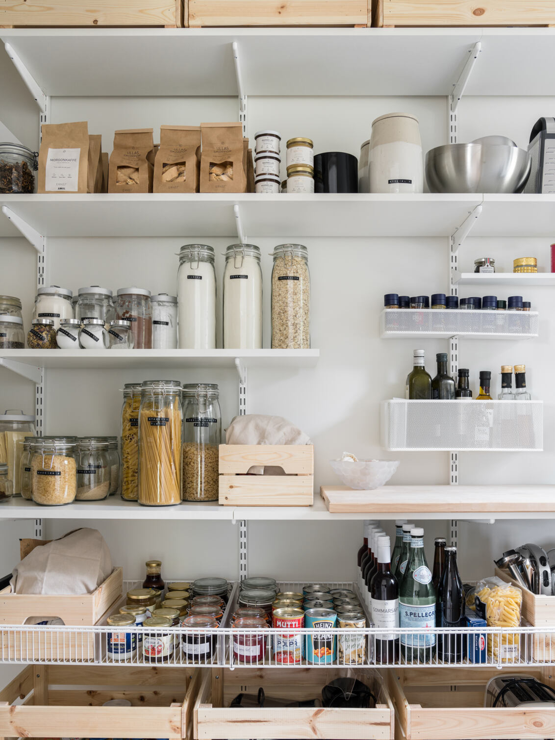 Classic by Elfa -säilytyskalusteita, joissa on hyllyjä, lankakoreja ja verkkokoreja, jotka sisältävät erilaisia elintarvikkeita.