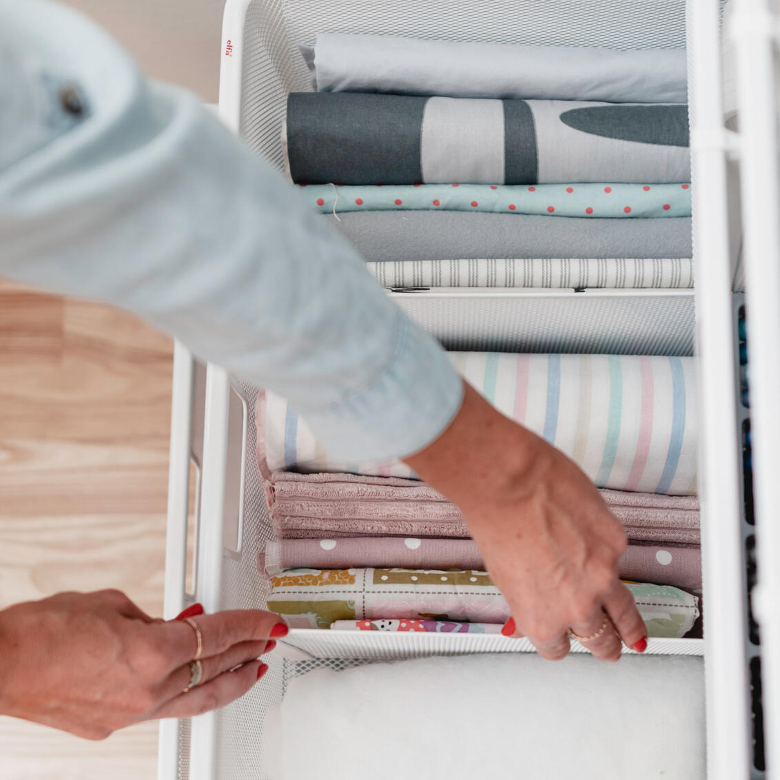 Skrzynka druciana Elfa ze starannie uporządkowanymi tkaninami i materiałami tekstylnymi