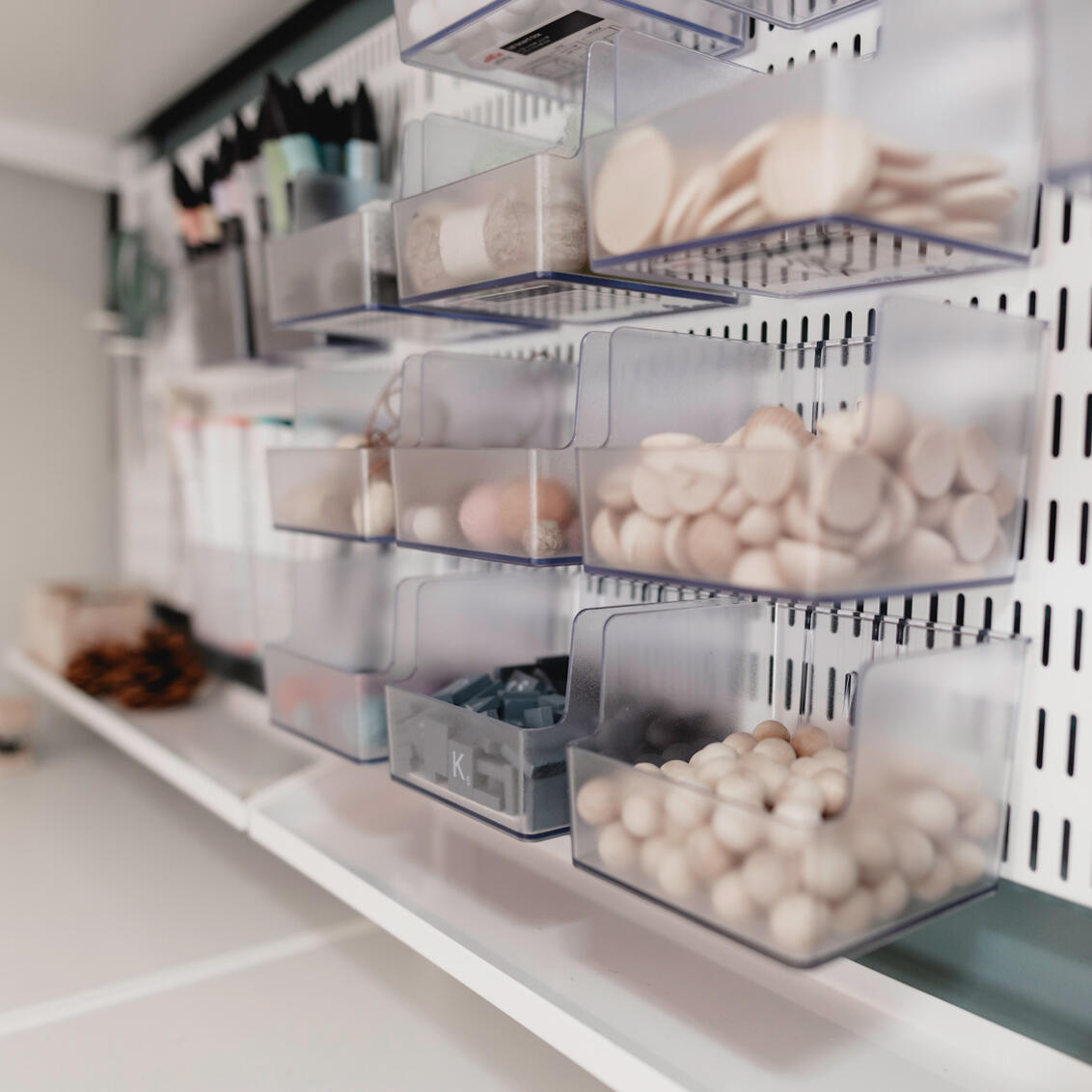 Przezroczyste pudełka do przechowywania Elfa z materiałami rzemieślniczymi na półkach ściennych