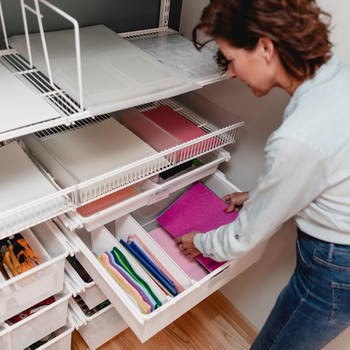 Kobieta wybiera kolorowy papier z systemu skrzynek drucianych Elfa