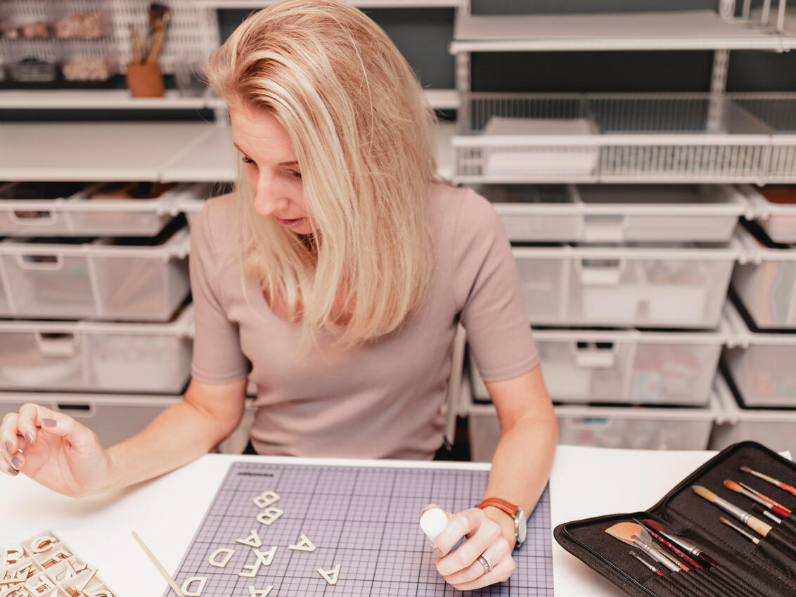 Kobieta tworząca przy biurku z systemem przechowywania Elfa w tle