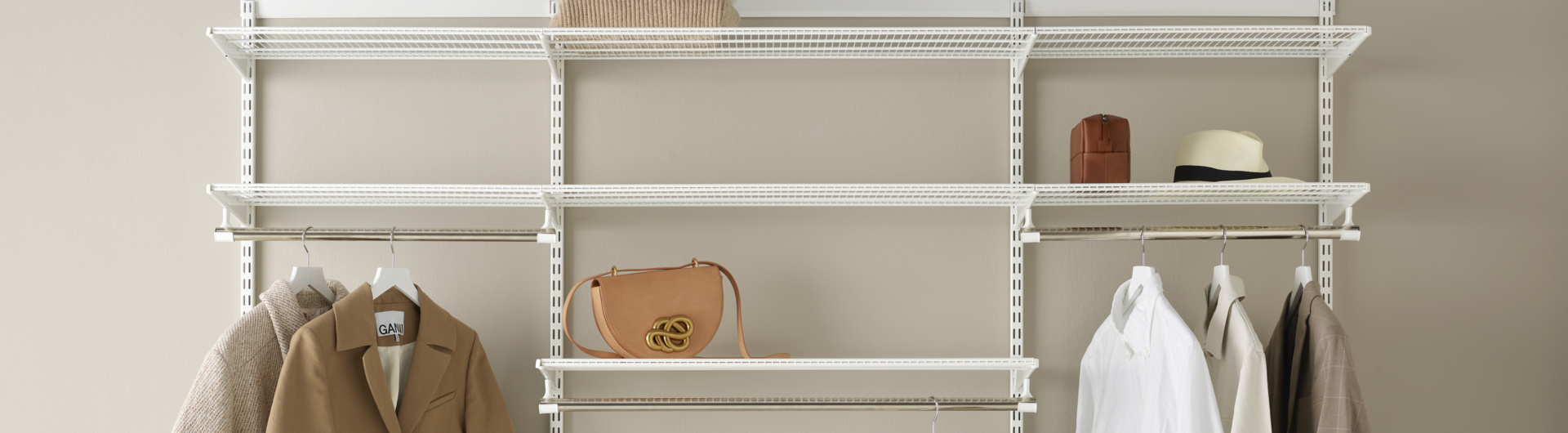 Offener Classic by Elfa Kleiderschrank in Weiß mit Gitterböden und hängender Kleidung.