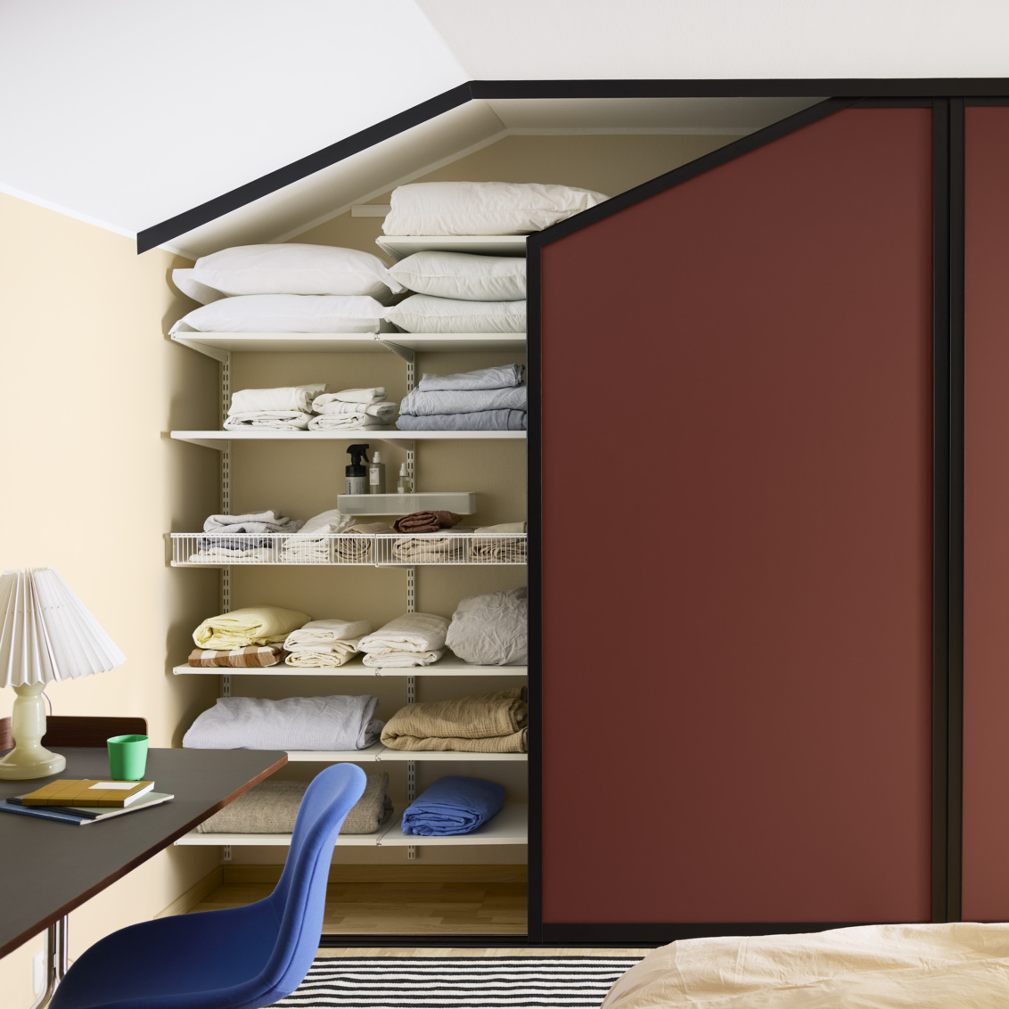 Makuuhuone, jossa on viininpunaiset Elfan liukuovet viistokatossa olevassa vaatekaapissa.