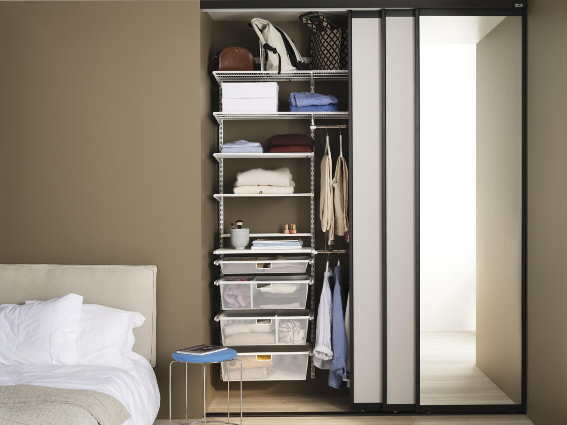 Schlafzimmer mit Kleiderschrank von Elfa mit Drahtböden, ausziehbaren Mesh-Schubladen und Schiebetüren Vista.