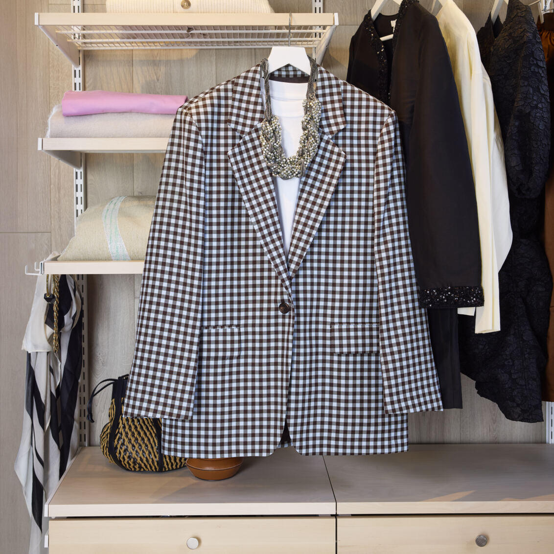 En Décor+ garderobe fra Elfa i hvit og bjerk, der et antrekk er klar på en kleshenger.