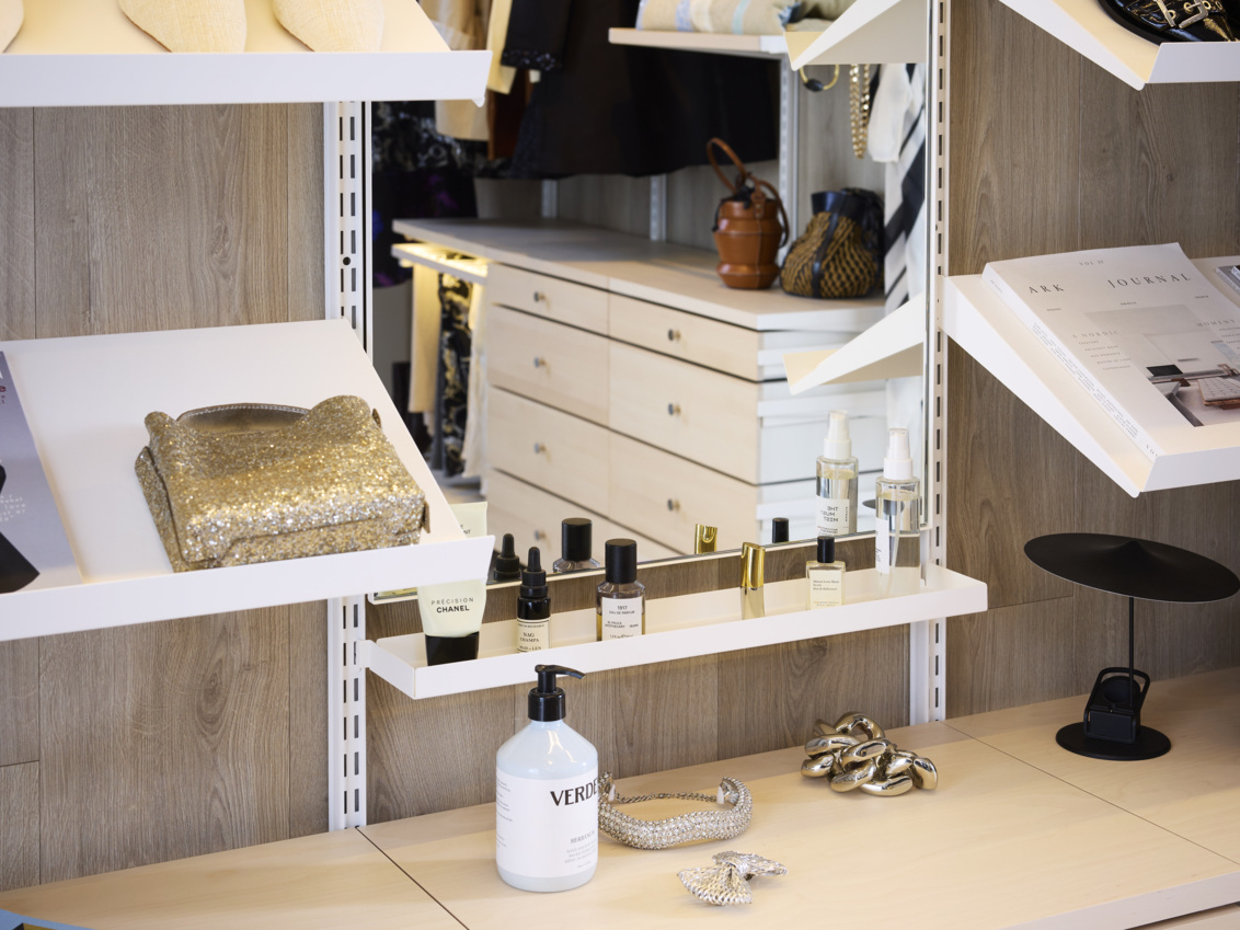  Walk-in vaatekaappi, jossa on Décor+ peili ja sen ympärillä viistot hyllyt, joilla on asusteita.