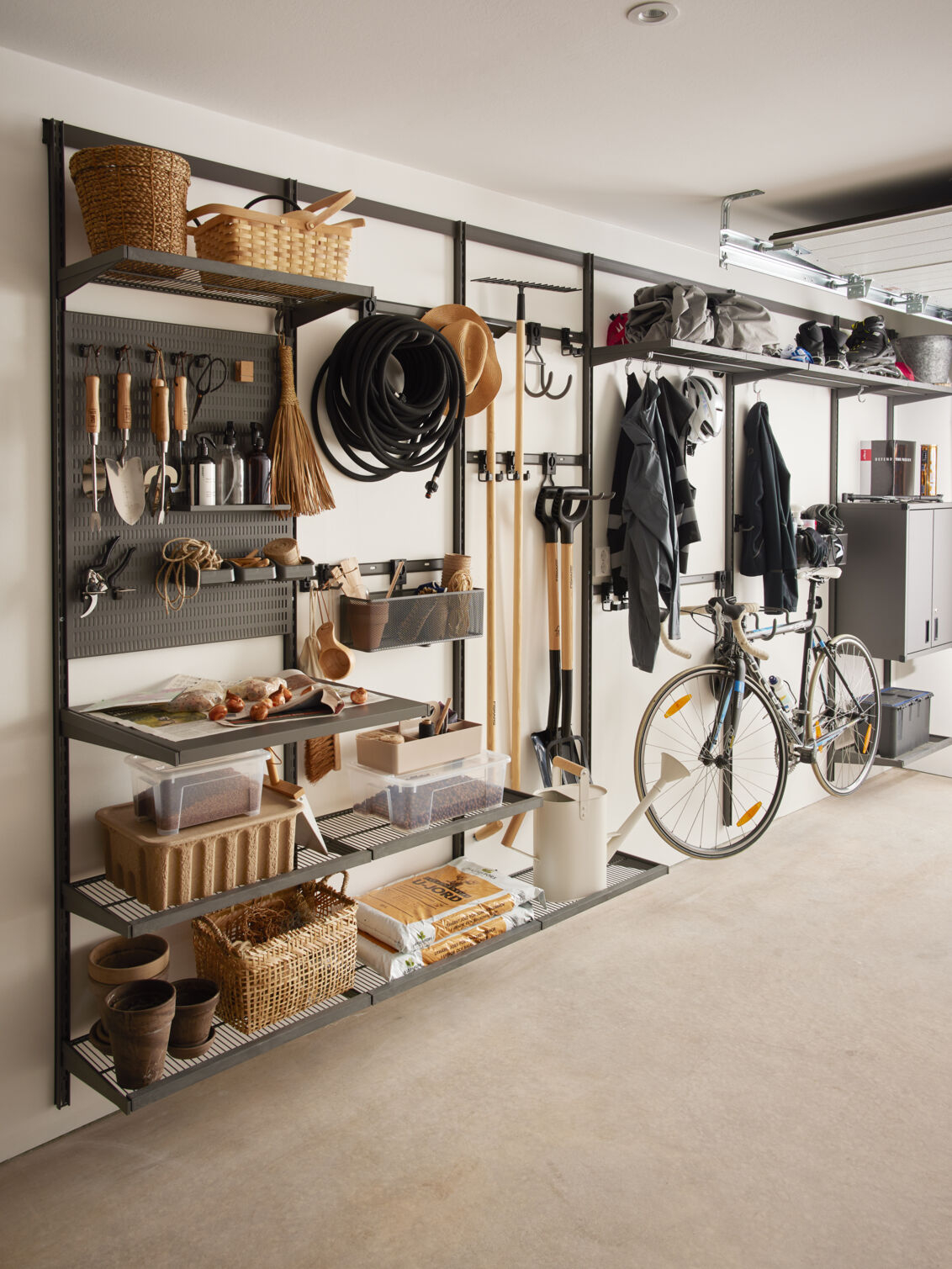 Garage+ by Elfa -säilytyskalusteiden sisältävä autotalli, jossa säilytetään puutarhatyökaluja.