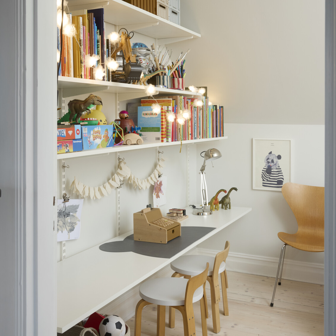 Lastenhuone, jossa on kirjahylly vinokaton alla täynnä kirjoja ja leluja. Alin hylly toimii työpöytänä.