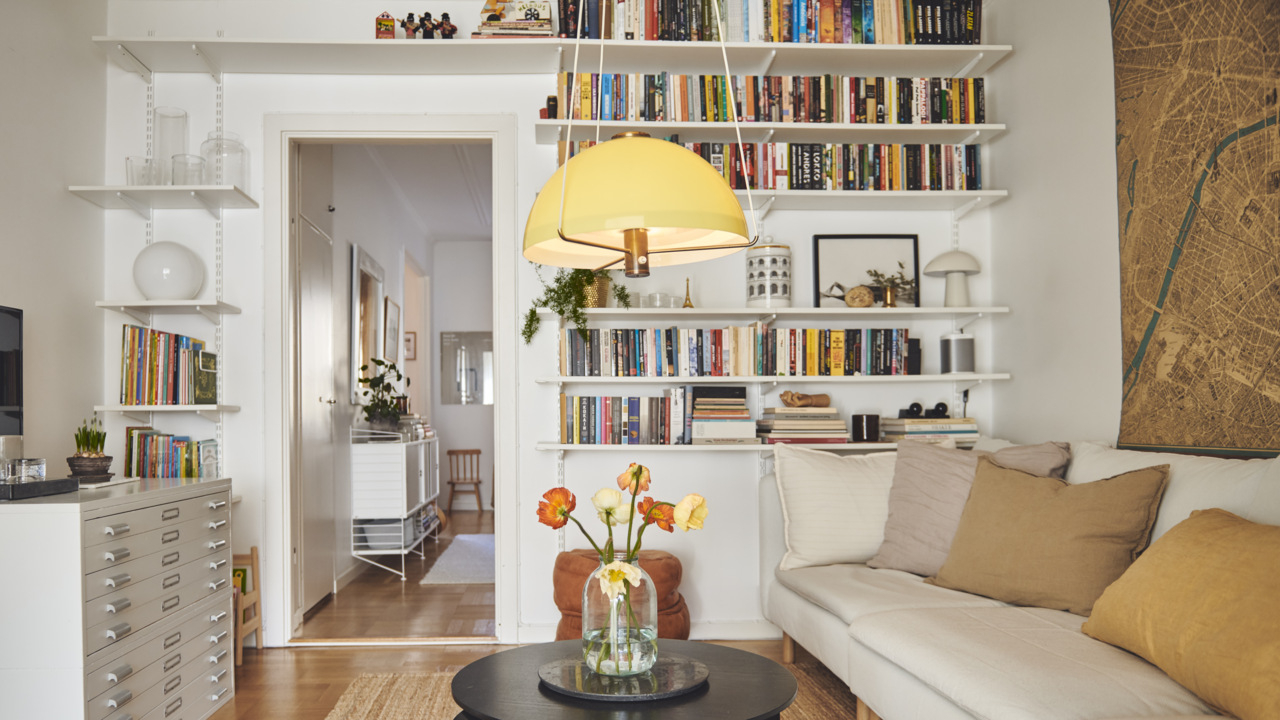 Salon z sofą, stolikiem kawowym, komodą i regałem Sparring Elfa okalającym drzwi.