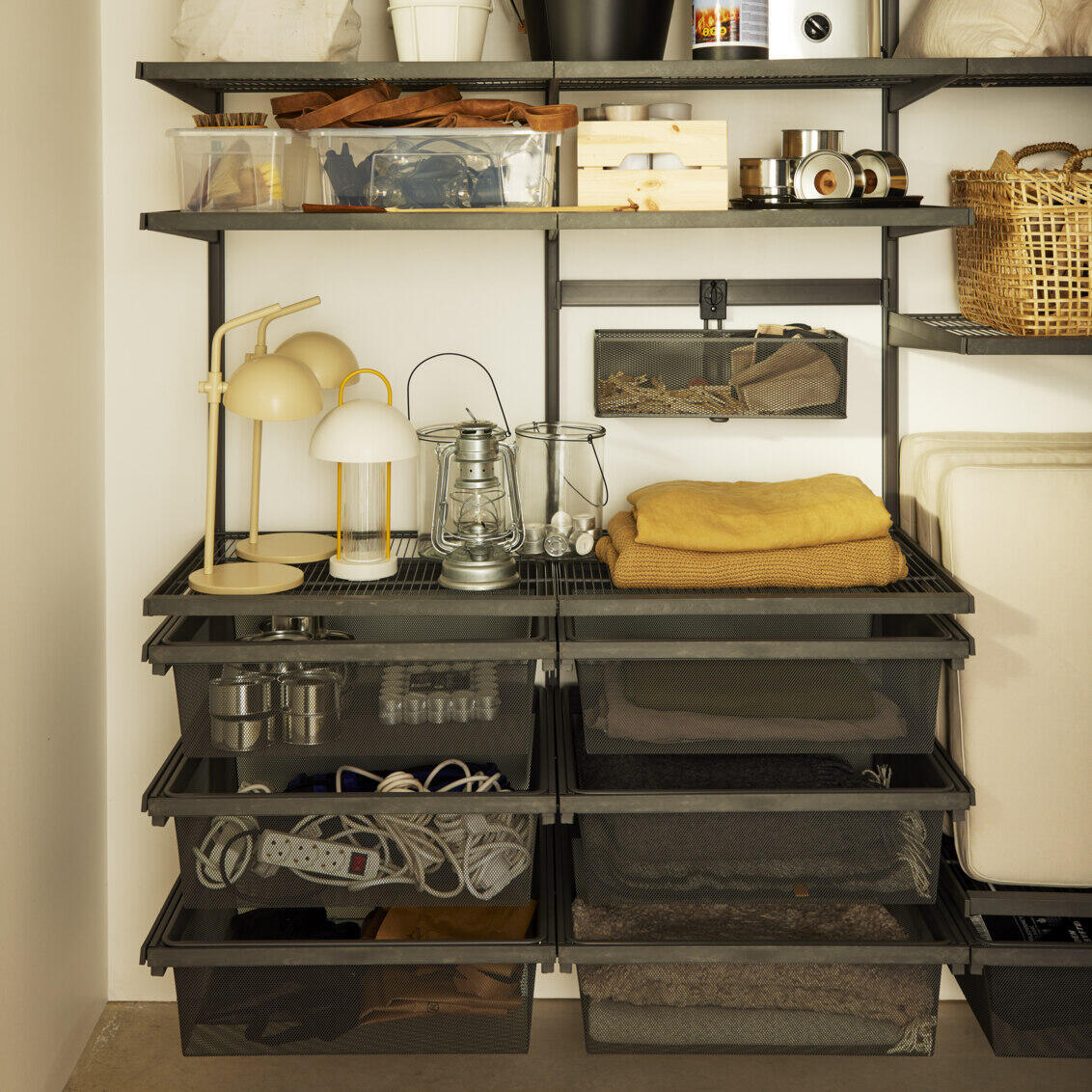 Garage+ by Elfa storage with wire shelves and mesh trays to store blankets, lamps and other items.