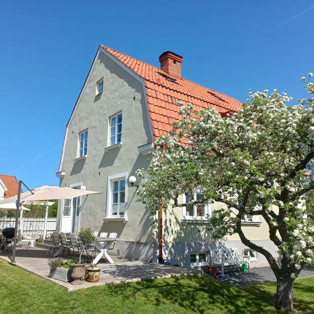 Et tjuetalls hus i en frodig hage på en solrik dag.