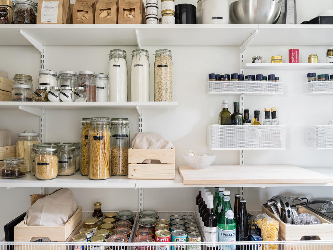 Classic by Elfa -säilytyskalusteita, joissa on hyllyjä, lankakoreja ja verkkokoreja, jotka sisältävät erilaisia elintarvikkeita.