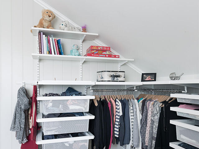 Clothes and shoes storage on wall-hung shelves and trays in white interior.