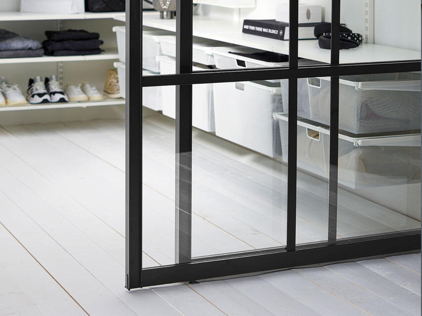 Vapaasti roikkuvat liukuovet tilanjakajina mustassa profiilissa lasitäytteellä.