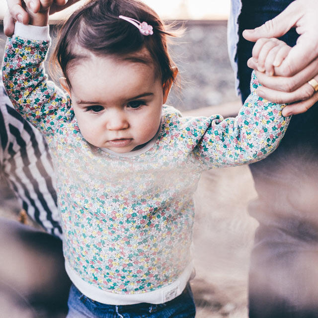 Niña caminando con la ayuda de una mujer.