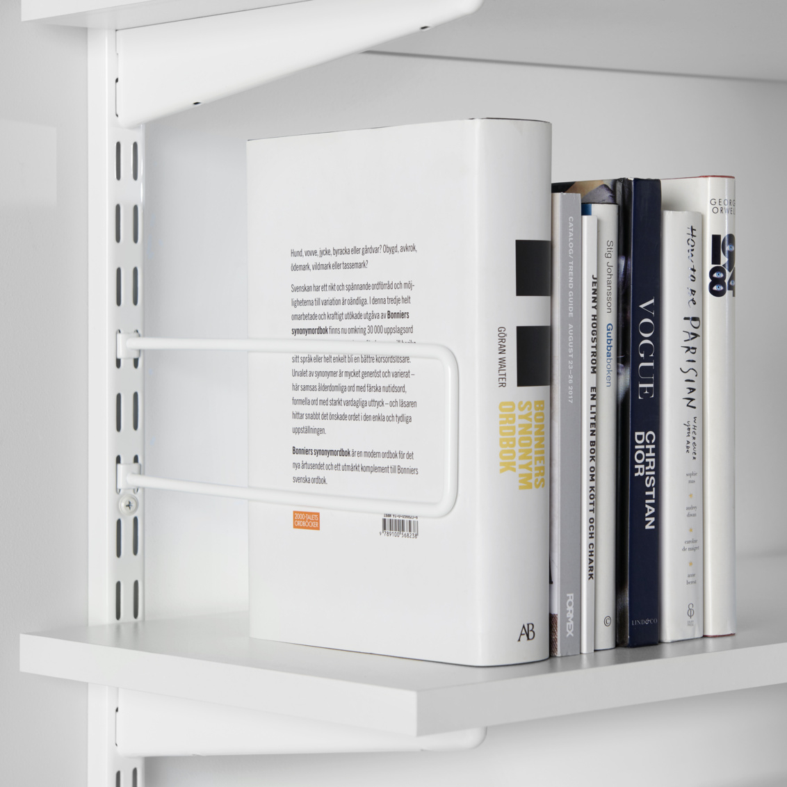 Książki utrzymywane na miejscu za pomocą podpórki do książek Sparring na szynę ścienną firmy Elfa.