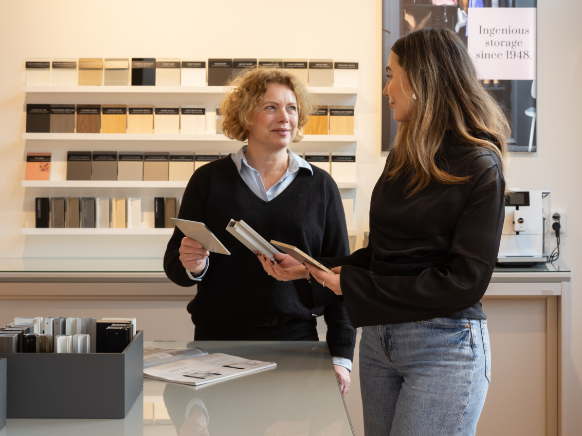 To kvinder diskuterer forskellige farve- og materialevalg til skydedøre.