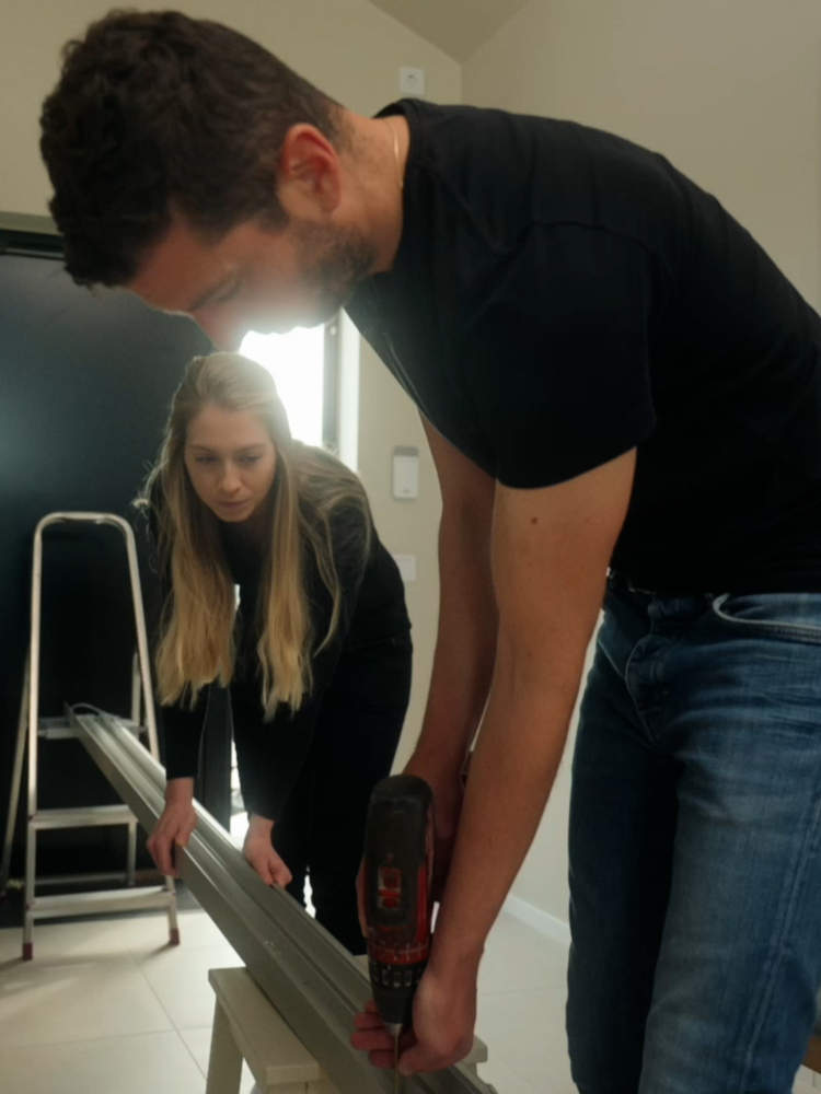 En jente og en gutt borer en skinne til skyvedører fra Elfa.