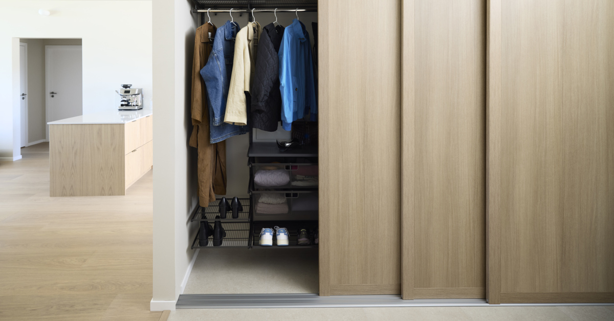 Eteinen, jossa on Elfa-vaatekaappi ja Grace-liukuovet, joiden täyte on vaaleaa tammea.