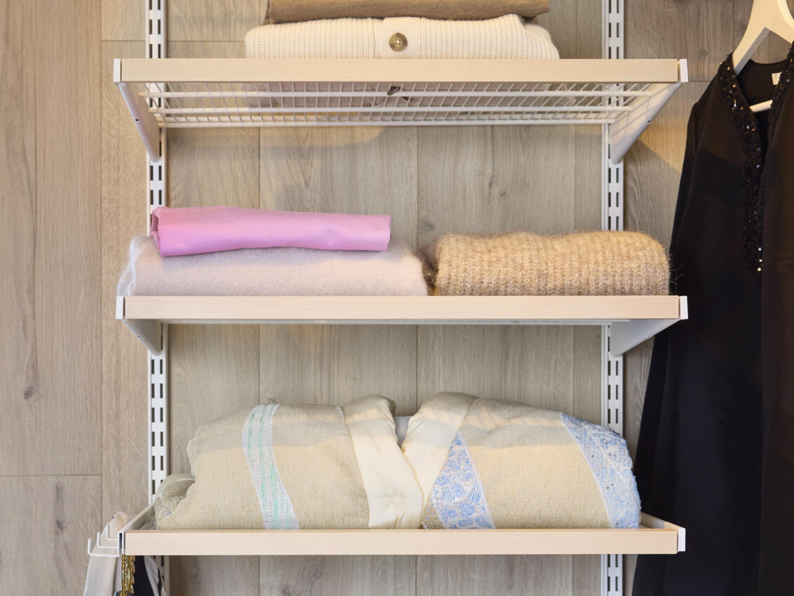 Elfan valkoiset ja koivunväriset Décor+ lankahyllyt, joilla on taiteltuja puseroita.